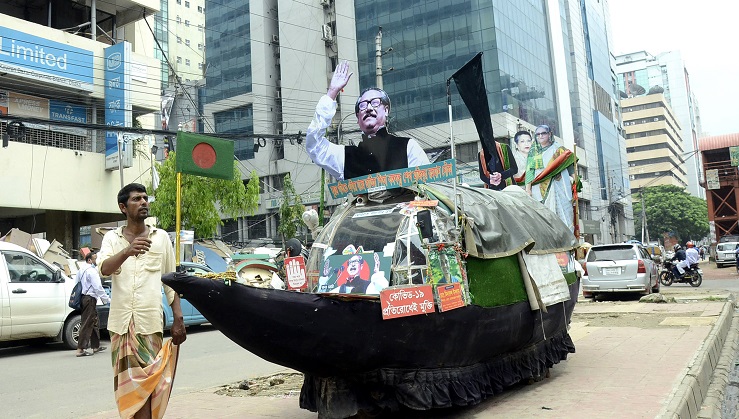 বঙ্গবন্ধুর ভাস্কর্য সম্বলিত নৌকার আদলে তৈরি একটি বাহন নিয়ে রাজধানীর বিভিন্ন সড়কে সচেতনতামূলক প্রচারে নেমেছেন খুলনার কয়রা উপজেলার মিনারুল ইসলাম। ছবিটি কারওরান বাজার থেকে তোলা।